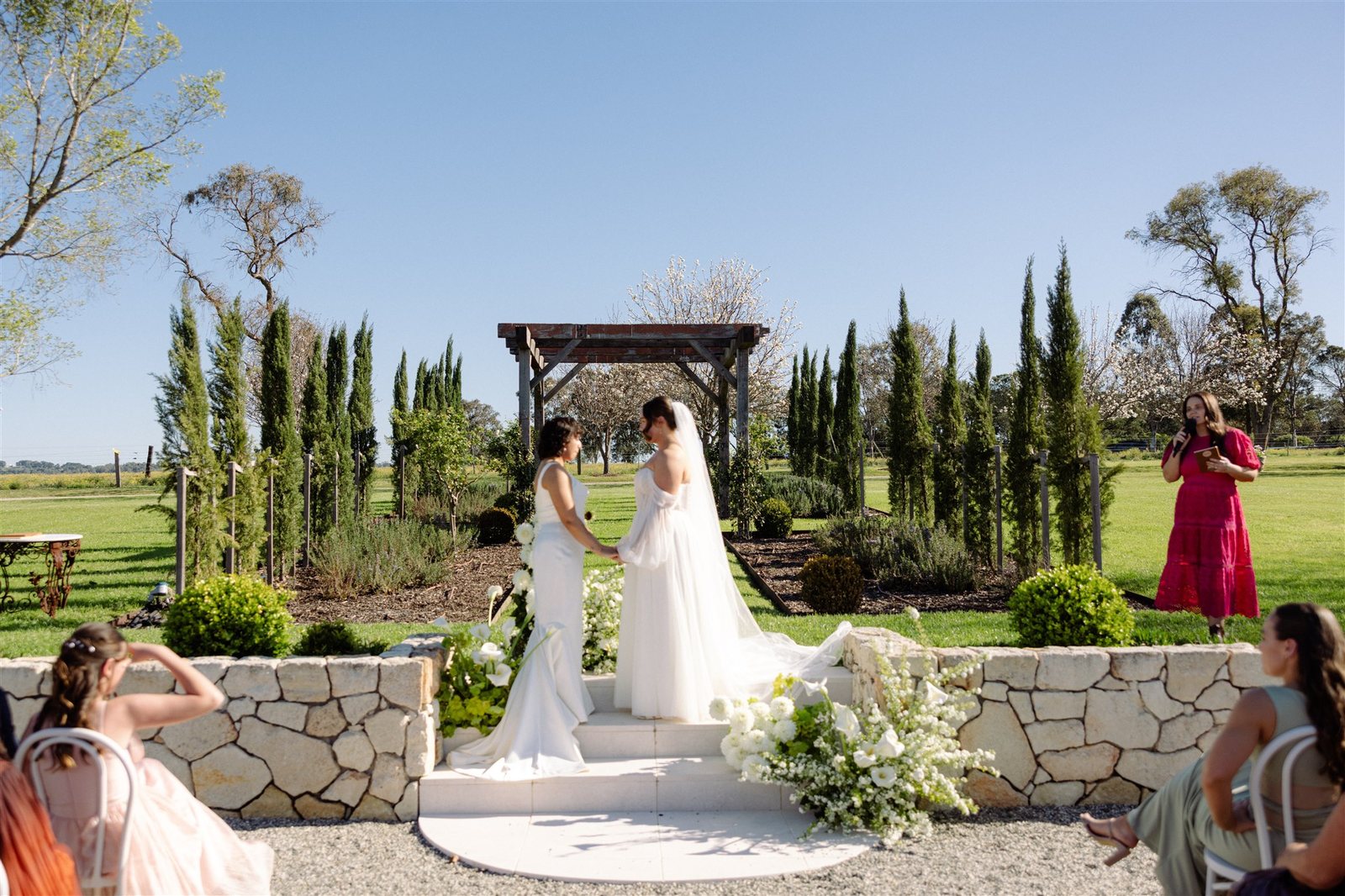 A bride walking the Ceremony Garden aisle between pencil pines