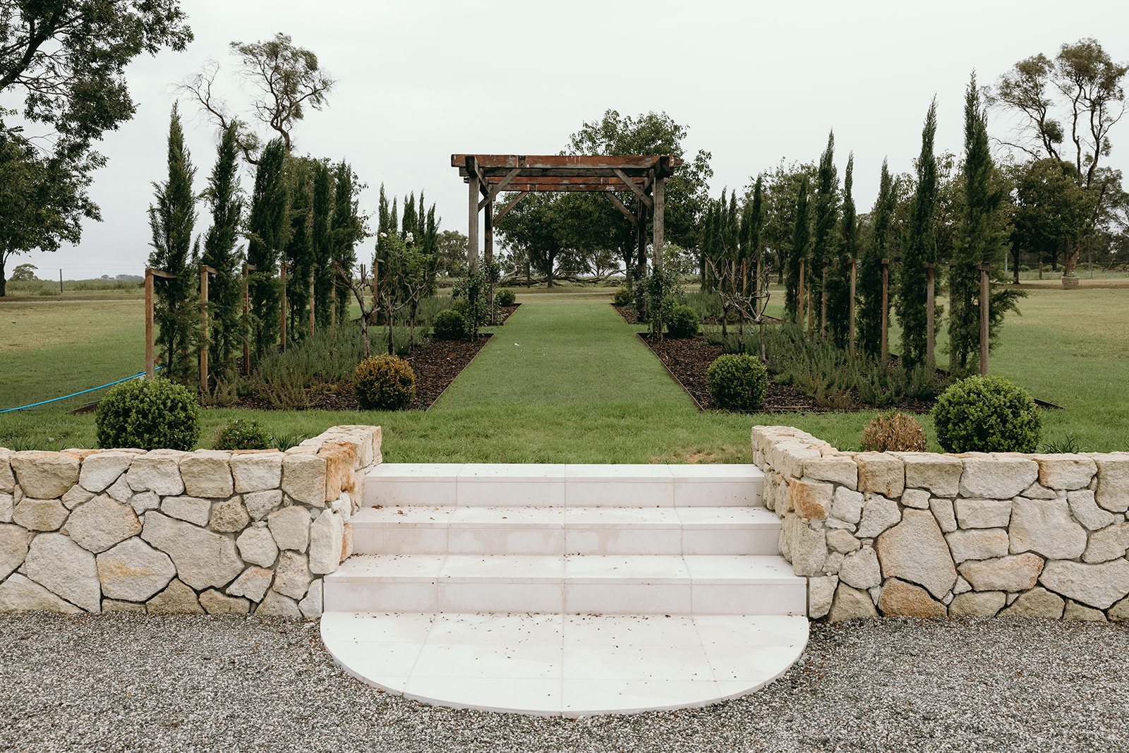 The Ceremony Garden: limestone steps, pencil pines and the pergola aisle