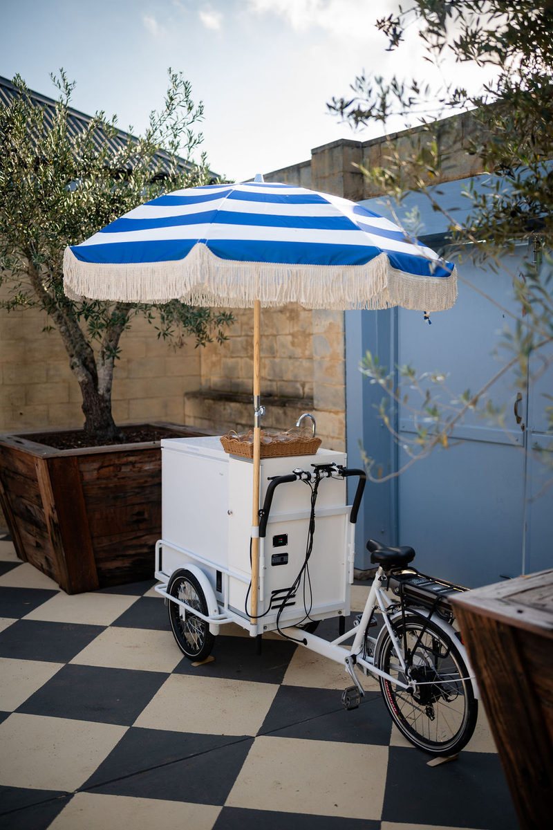 The gelato bike with its striped umbrella on the checkerboard