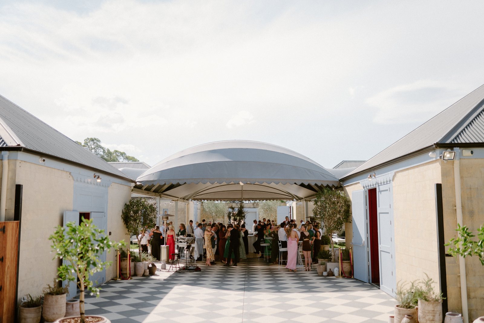The piazza through its arches, guests on the checkerboard